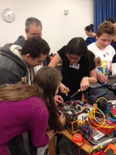 Youngsters leaning iover a robot to fix problems