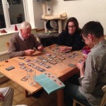 Three generations playing a board gamee.