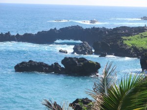 Black lava rock surrounded by sea