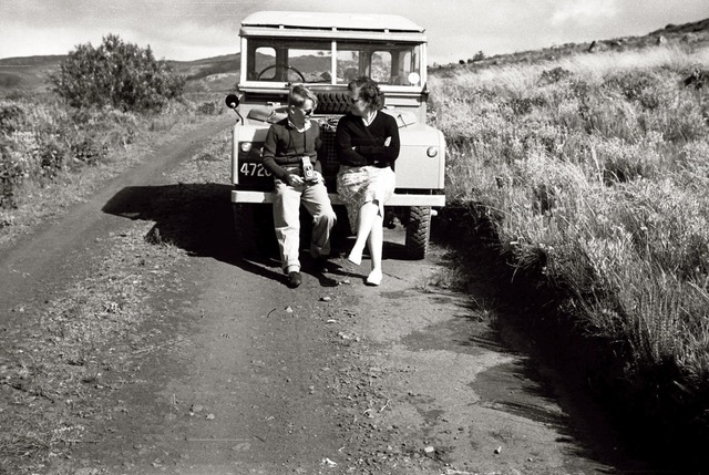 Mother and son sitting on front bumper of land rover