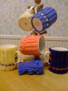 Mugs wrapping knitted cosies on mug stand